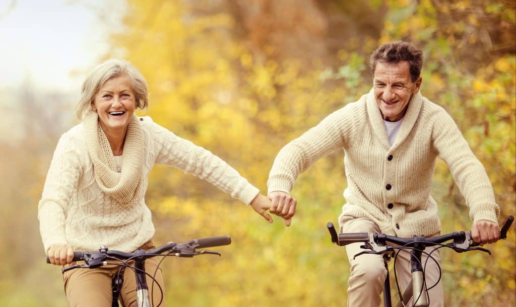 An elderly couple riding bikes together.