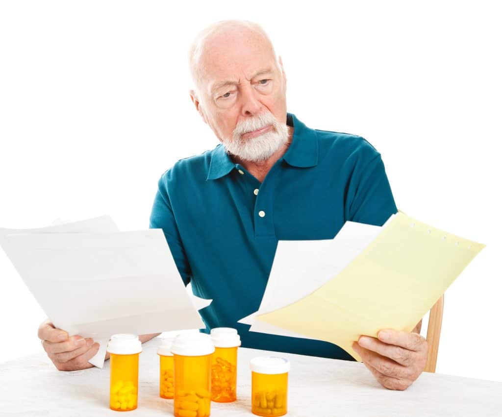 An elderly man comparing Medicare plans and costs.